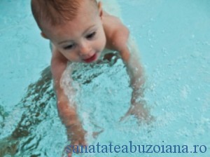 Swimming baby boy reaches for blue ball